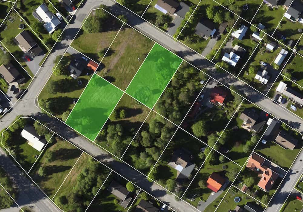 Övergripande flygbild över ett bostadsområde med obebyggda tomter och utritade tomtgränser