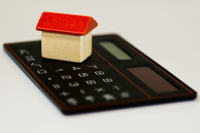 Miniatyrmodell av ett hus står på en svart miniräknare