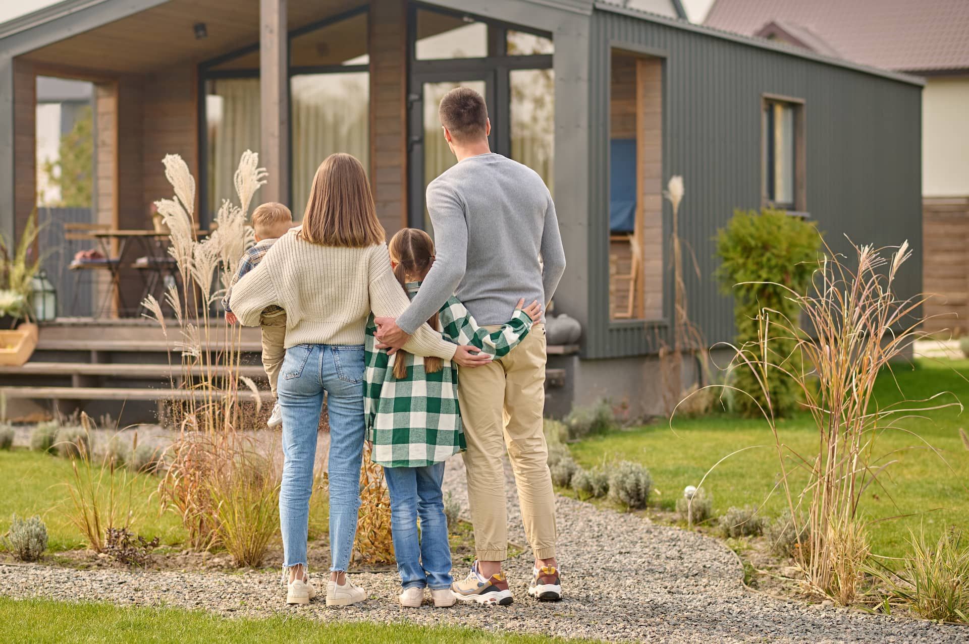 En familj står och håller om varandra utanför sitt nybyggda hus