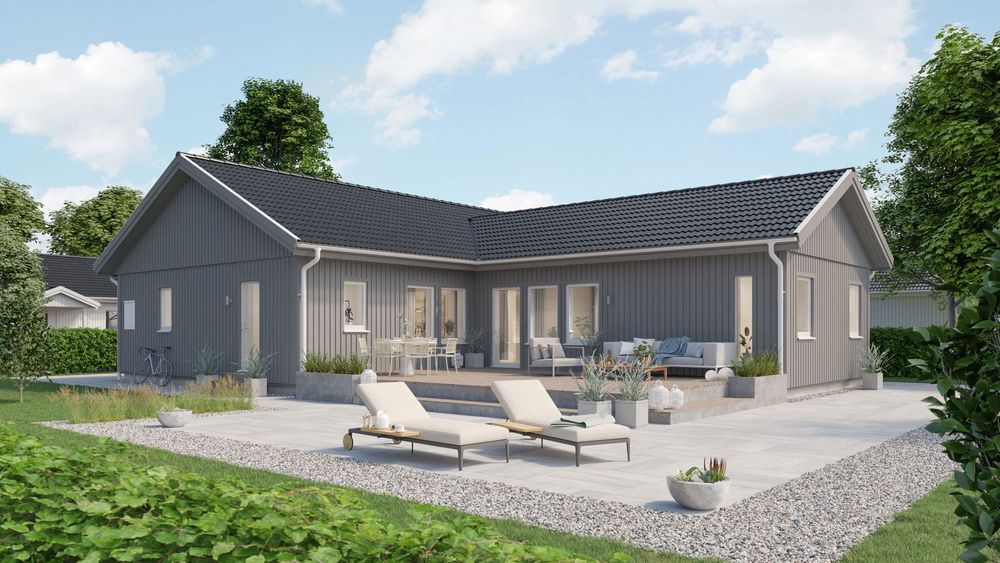 Ett vitt enplanshus med en blommig terass under en sommarkväll